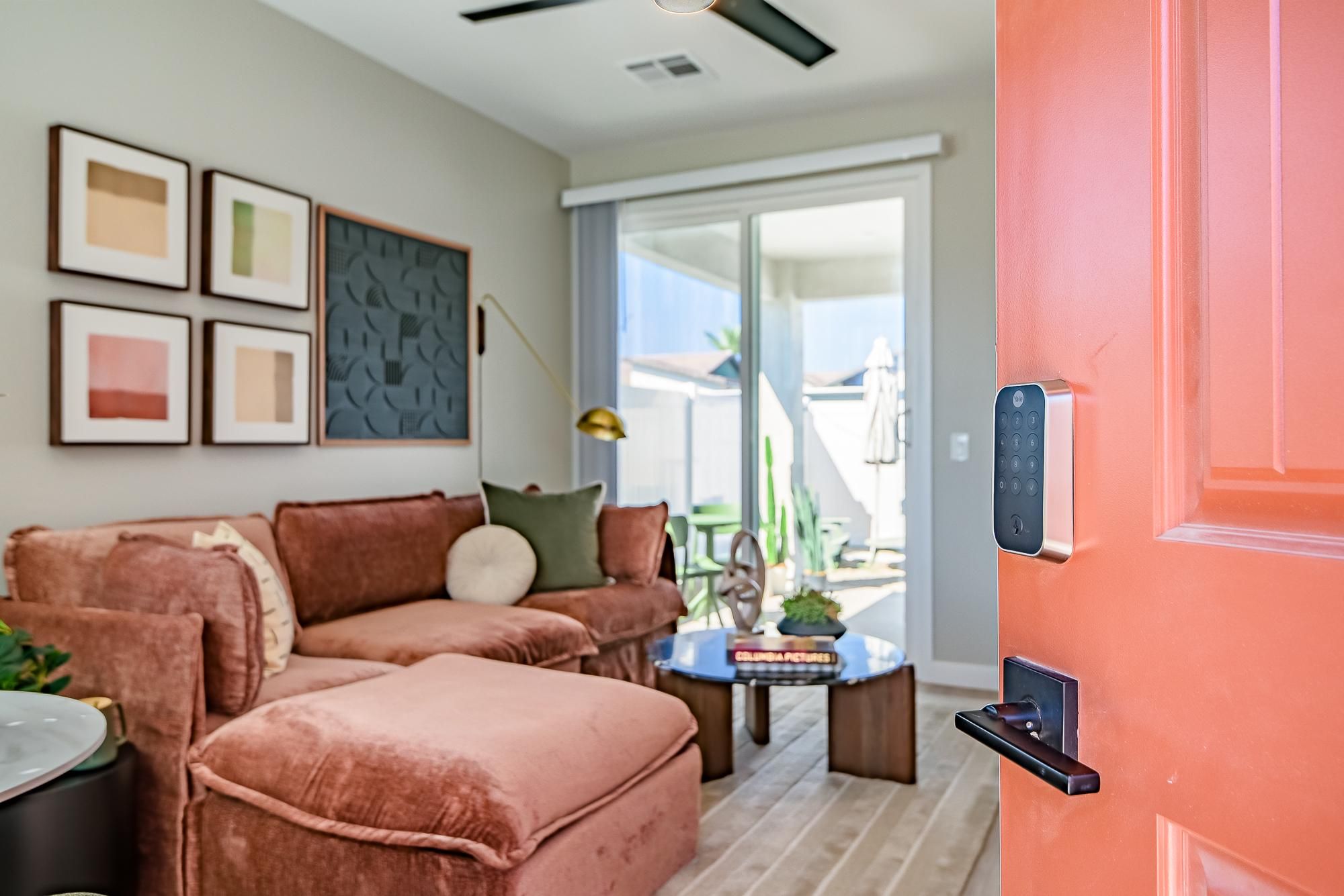 Sonita apartments Living room with a brown sectional sofa, wall art, glass coffee table, and sliding glass doors to a patio.
