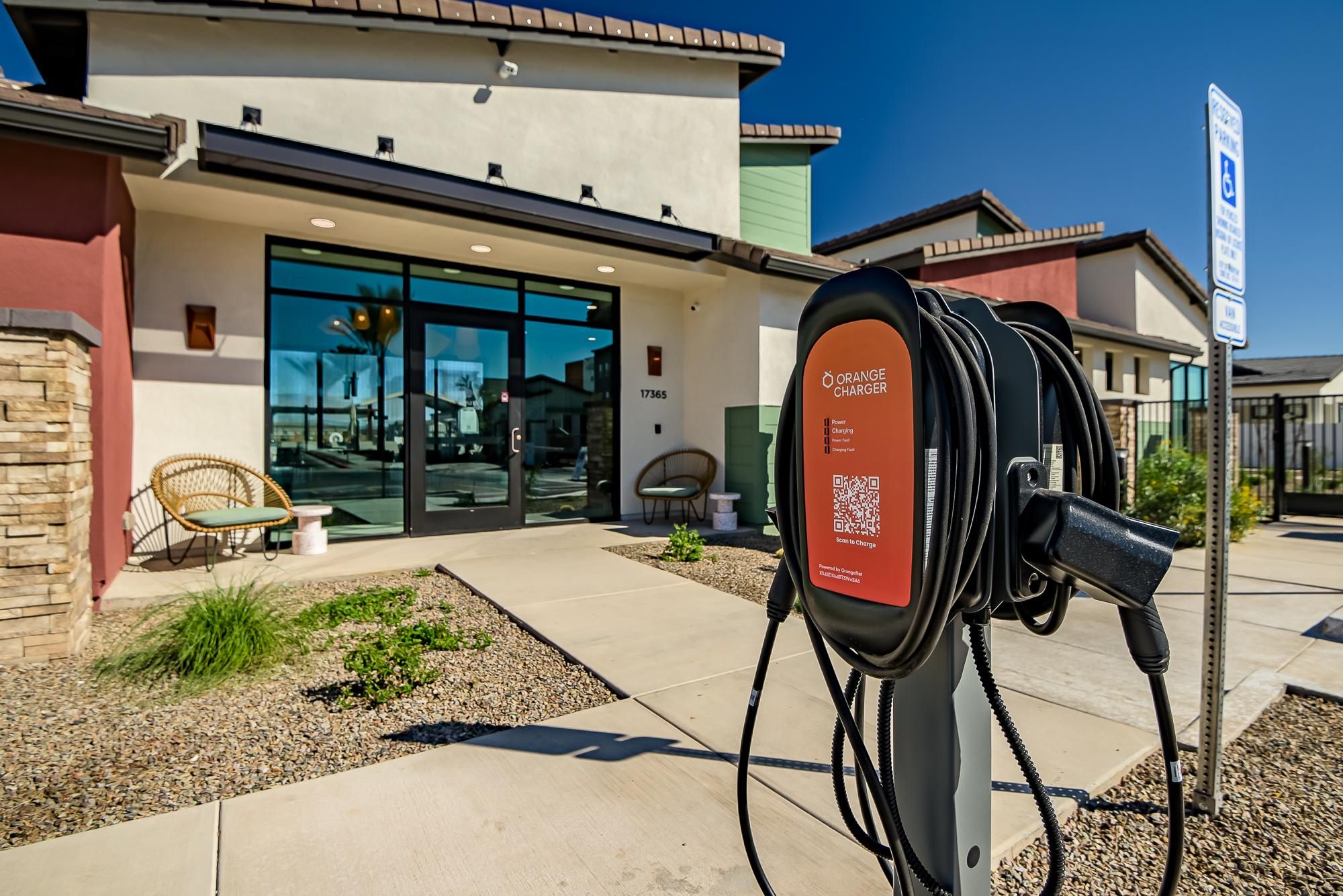 Sonita apartments EV charging station outside a modern building with seating and accessible parking under a clear blue sky.