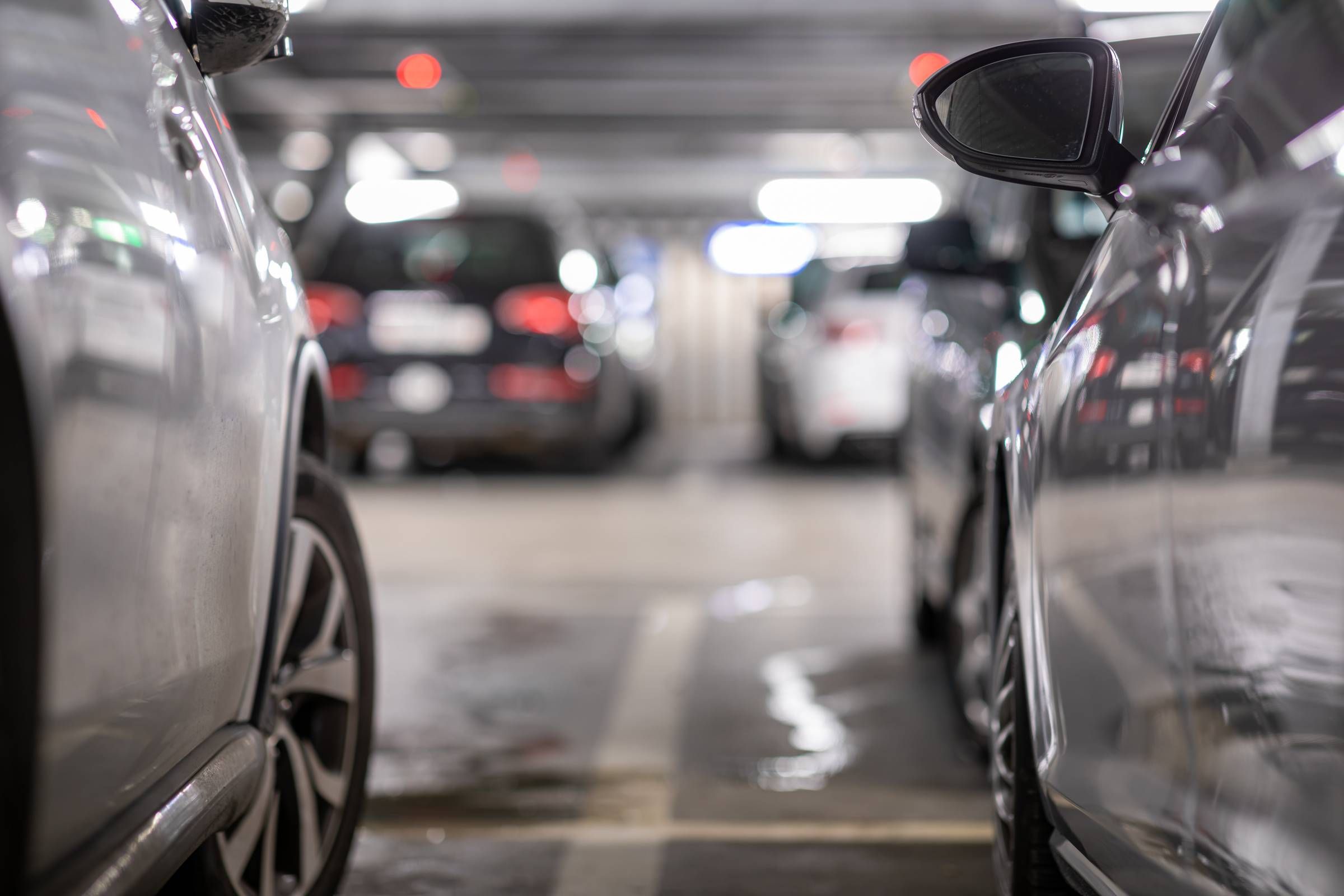 Sonita apartments Close-up of parked cars in a blurry, indoor parking garage with bright overhead lights.