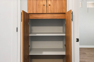 Sonita Open wooden cabinet with empty shelves and two closed compartments at the top.